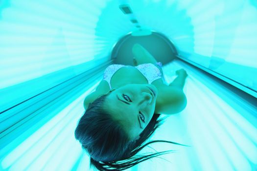Beautiful young woman have tanning skin treatment in modern solarium