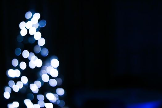 Christmas time and holiday mood concept. Blurred blue xmas tree lights as bokeh background.