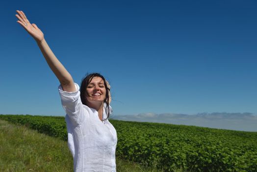 Young happy woman in green field with blue sky in background