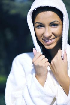 Pretty Young woman take a steam bath treatment at finish wooden sauna while wearing white towel