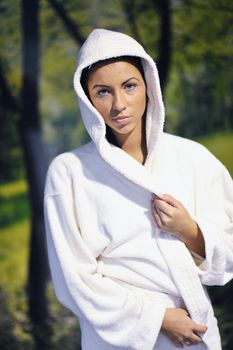 Pretty Young woman take a steam bath treatment at finish wooden sauna while wearing white towel