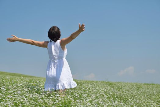 Young happy woman in green field with blue sky in background