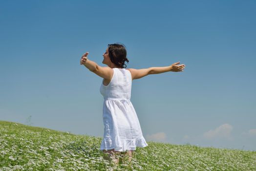 Young happy woman in green field with blue sky in background