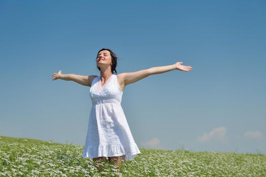 Young happy woman in green field with blue sky in background