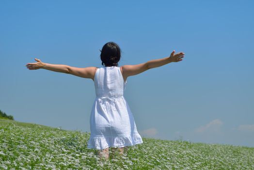 Young happy woman in green field with blue sky in background
