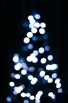 Christmas time and holiday mood concept. Blurred blue xmas tree lights as bokeh background.