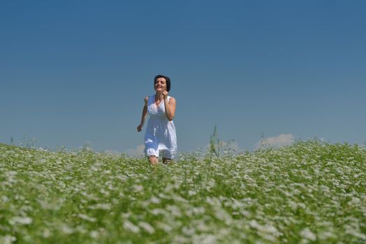 Young happy woman in green field with blue sky in background