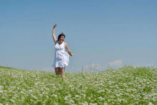 Young happy woman in green field with blue sky in background