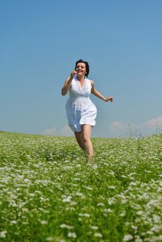 Young happy woman in green field with blue sky in background