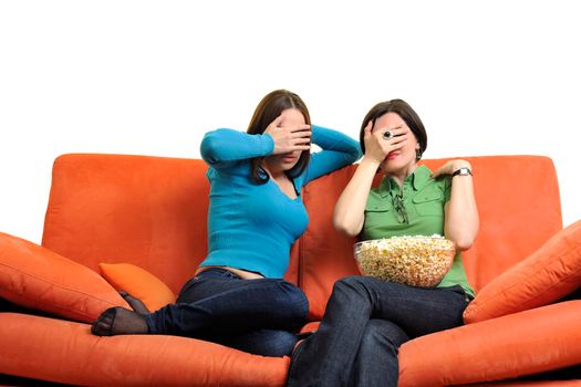 female friends eating popcorn and watching tv at home on orange sofa isolated on white