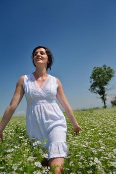 Young happy woman in green field with blue sky in background
