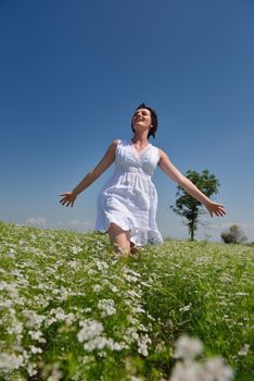 Young happy woman in green field with blue sky in background