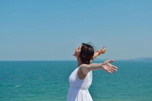 Happy  young woman with spreading arms, blue sky with clouds in background  - copyspace