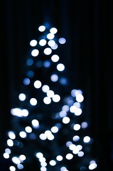 Christmas time and holiday mood concept. Blurred blue xmas tree lights as bokeh background.