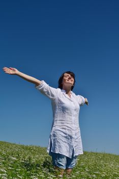 Young woman standing jumping and running  on a wheat field with blue sky in  background at summer day representing healthy life and agriculture concept