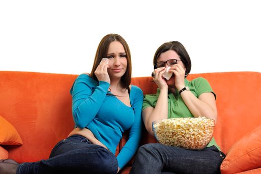 female friends eating popcorn and watching tv at home on orange sofa isolated on white