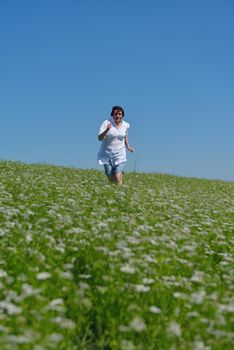 Young happy woman in green field with blue sky in background