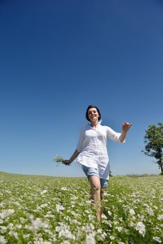 Young happy woman in green field with blue sky in background