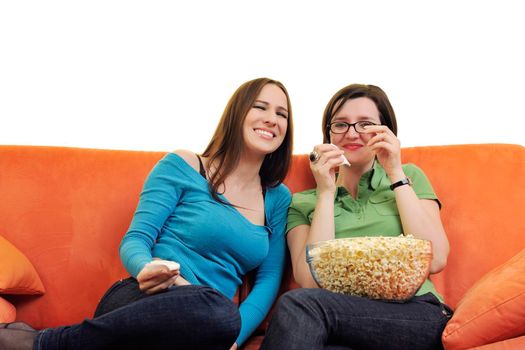 female friends eating popcorn and watching tv at home on orange sofa isolated on white