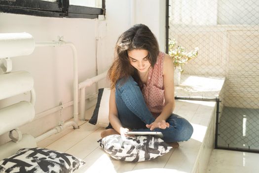 People, technology and internet concept - young woman using digital tablet at home.