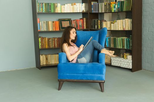 People, working and technology concept - relaxed young woman sitting on sofa with tablet.