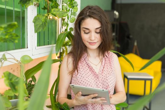 people, interior and education concept - young woman with a tablet in stylish apartment.