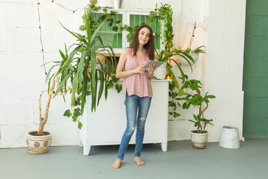 Technology and people concept - Young beautiful woman student standing near plants.