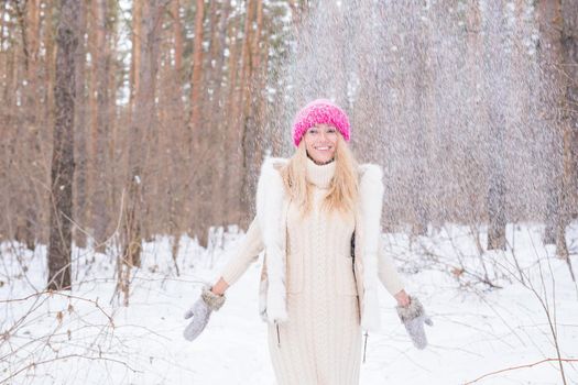 Portrait of young woman throwing the snow. Smiling girl walking in a winter park and having fun on a cold sunny day outdoors.