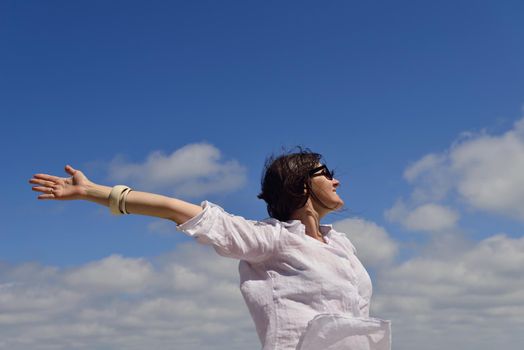 healthy Happy  young woman with spreading arms, blue sky with clouds in background  - copyspace