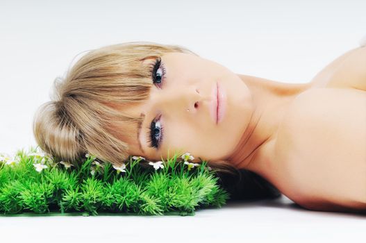 beautiful blonde woman face isolated on white with small green peace of grass
