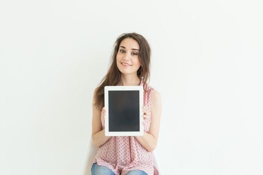 Business, technology and people concept - young woman showing empty screen in tablet on white background.