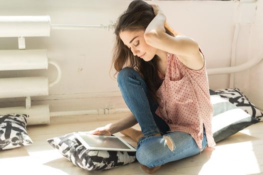 Leisure, technology and people concept - young brunette woman using tablet at home.