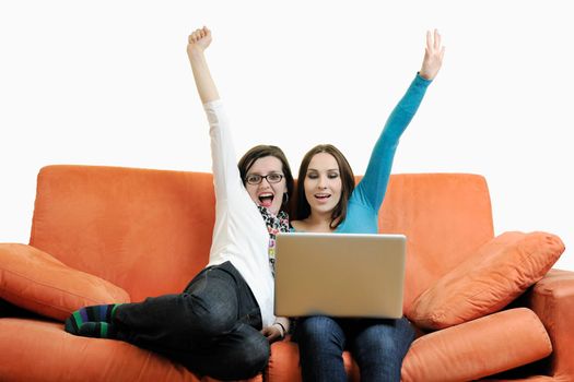 two happy young woman working on laptop computer on red sofa isolated on white