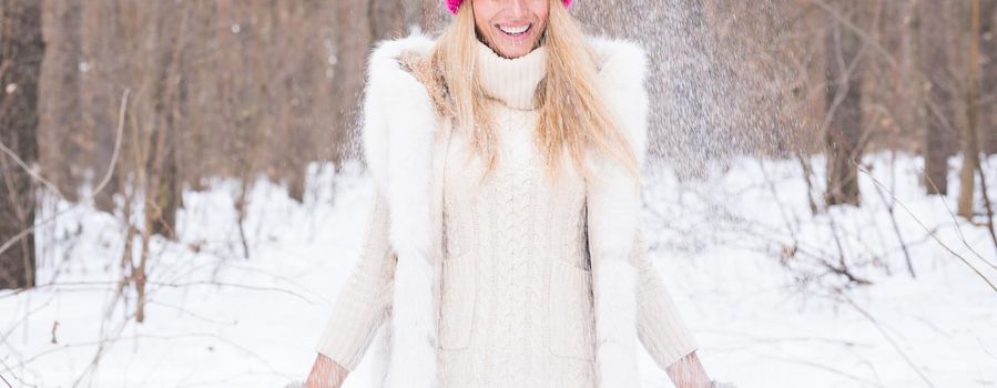 Fun, winter and people concept - Attractive woman dressed in white coat throwing snow