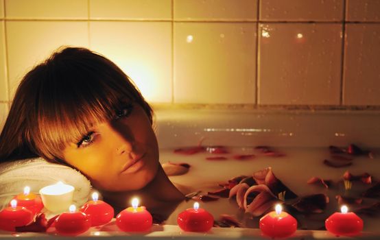 woman beauty spa and wellness treathment with red flower petals in bath