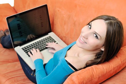young business woman in casual clothes working on laptop computer on orange sofa isolated on white