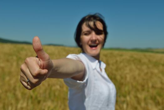 Young woman standing jumping and running  on a wheat field with blue sky the background at summer day representing healthy life and agriculture concept