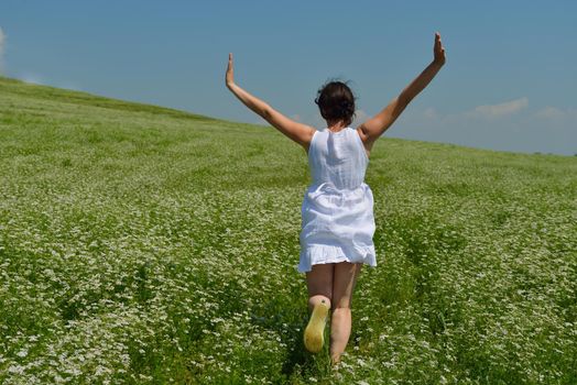 Young happy woman in green field with blue sky in background