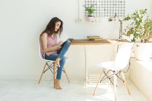 People, technology and internet concept - young woman using digital tablet at home.