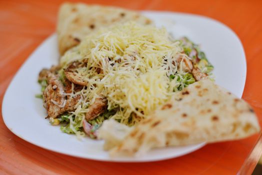 woman eat tasty chicken salad with fresh vegetables and cheese in retro kitchen