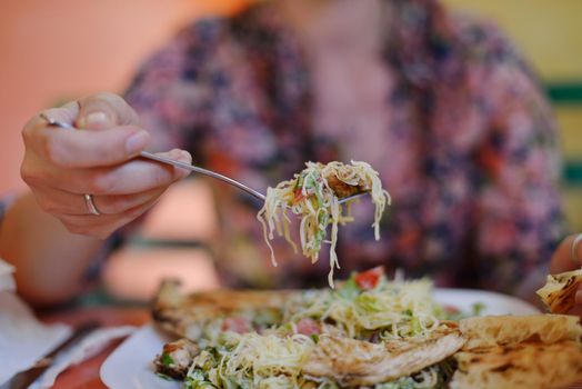 woman eat tasty chicken salad with fresh vegetables and cheese in retro kitchen