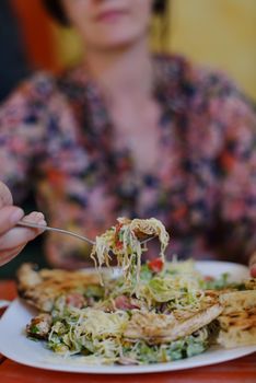 woman eat tasty chicken salad with fresh vegetables and cheese in retro kitchen