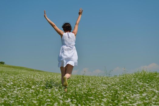 Young happy woman in green field with blue sky in background