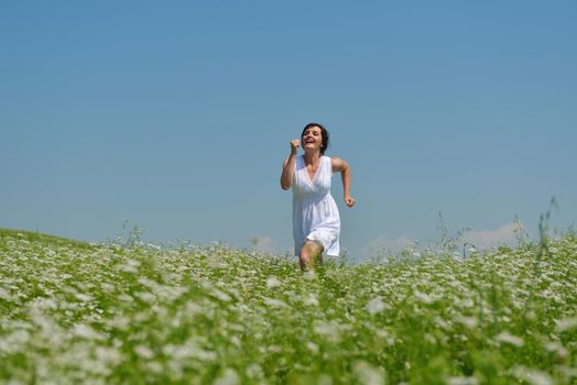 Young happy woman in green field with blue sky in background