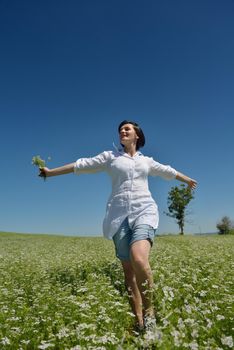 Young happy woman in green field with blue sky in background