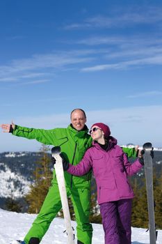 Portrait of happy couple at beautiful mountain on winter sunny day with blue sky and snow in background