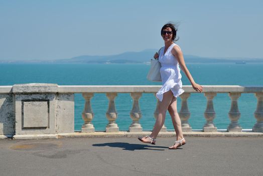 happy young tourist woman have fun while traveling araund city with blue sky and sea in background