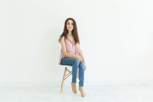 Beautiful female student sitting on a chair on white background with copy space.