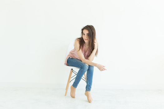 Beautiful brunette student woman sitting on a chair on white background with copy space.