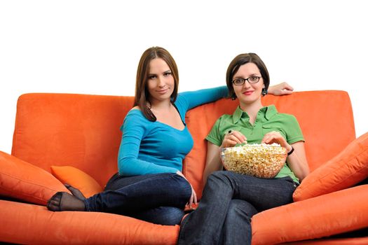 female friends eating popcorn and watching tv at home on orange sofa isolated on white